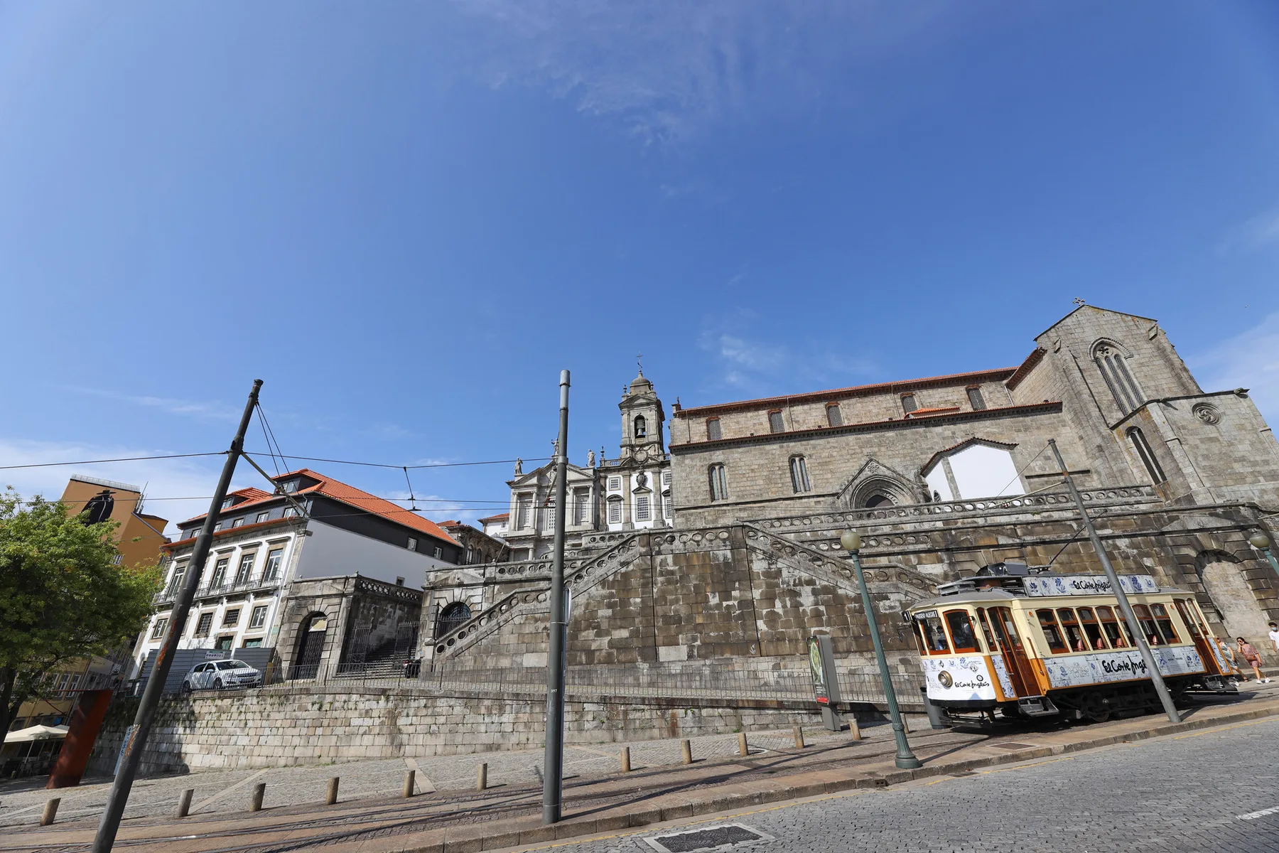 A stone church and neighboring historic buildings stand beside a city street.