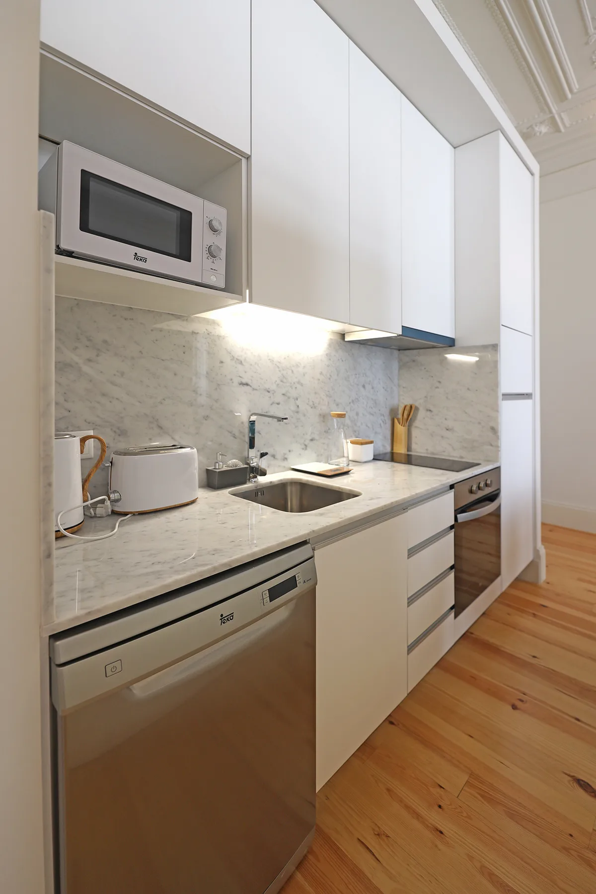 A modern kitchen with white cabinets, a countertop, and stainless steel appliances.