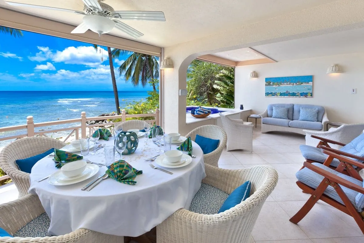 A bright seaside dining and sitting area opens onto a view of the ocean.
