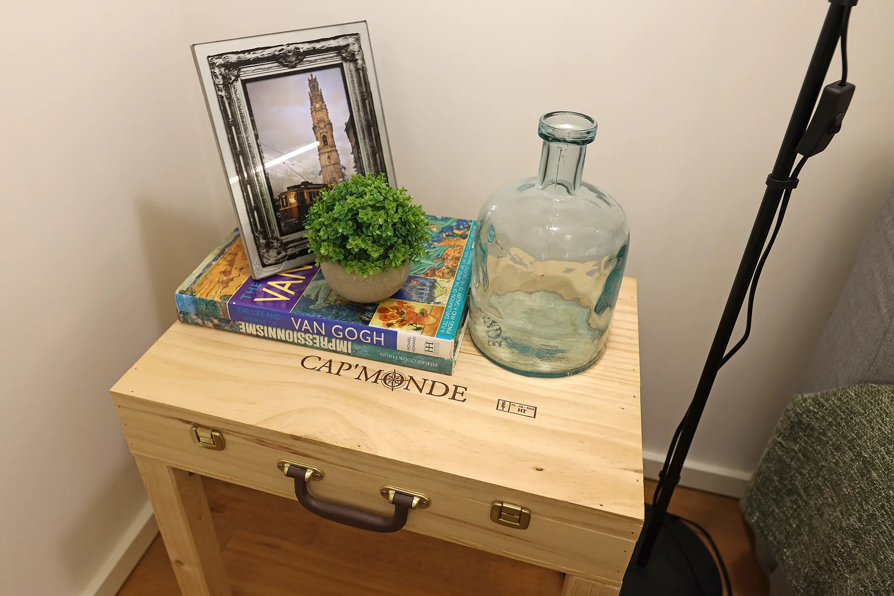 A wooden chest displays books, a small plant, a glass bottle, and a framed picture.
