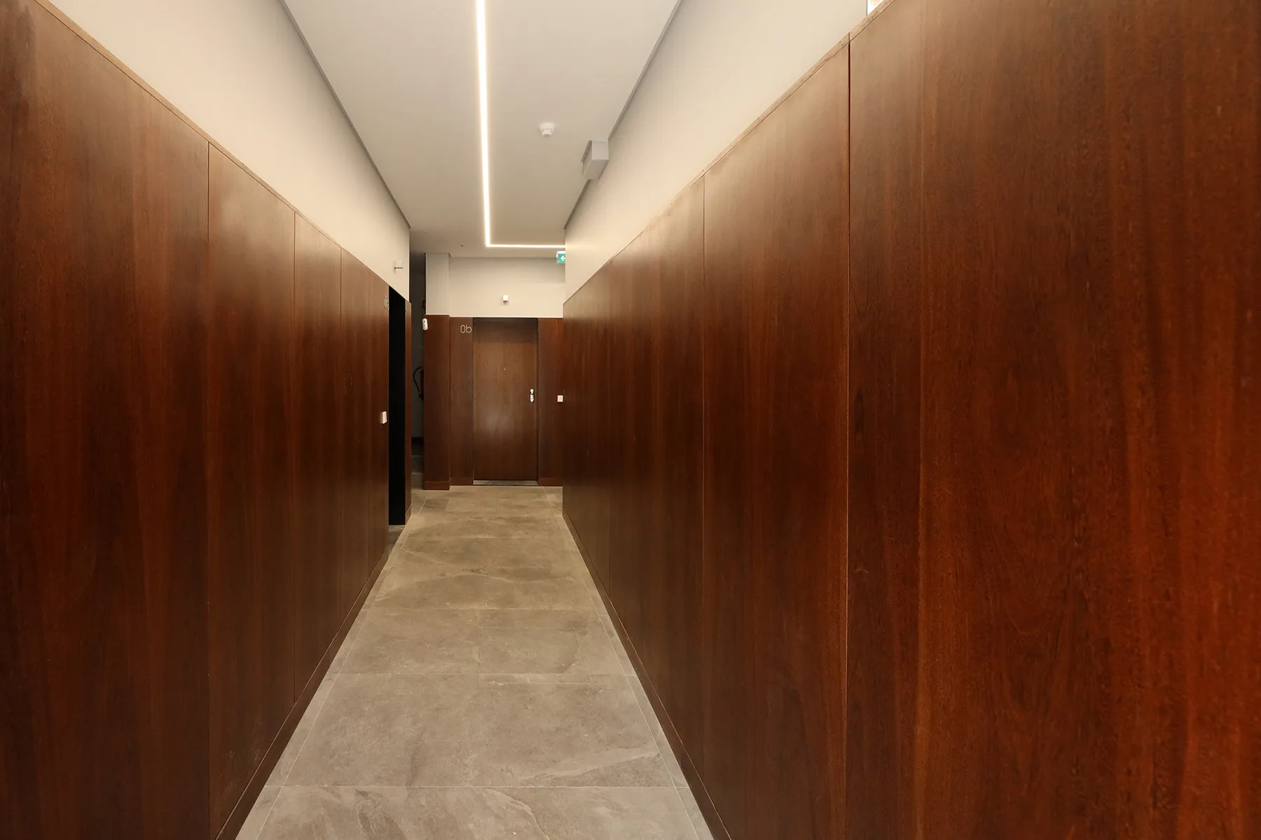 A narrow hallway with wood-paneled walls leads to a closed door.