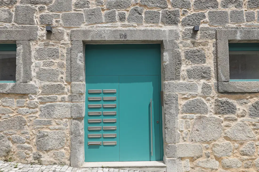 A turquoise entrance door set into a stone façade.