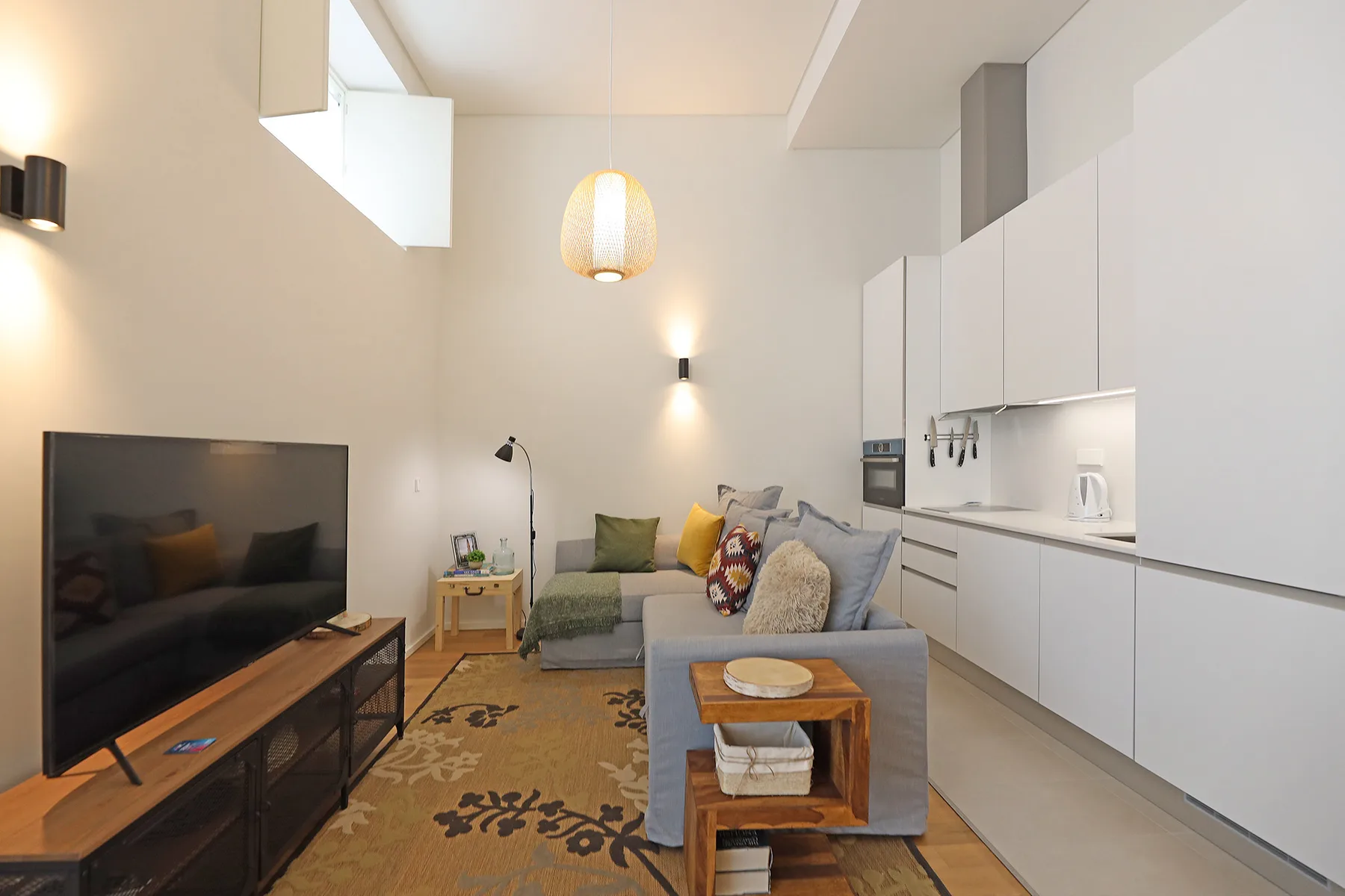 A living area with seating, a television, and a compact kitchen.