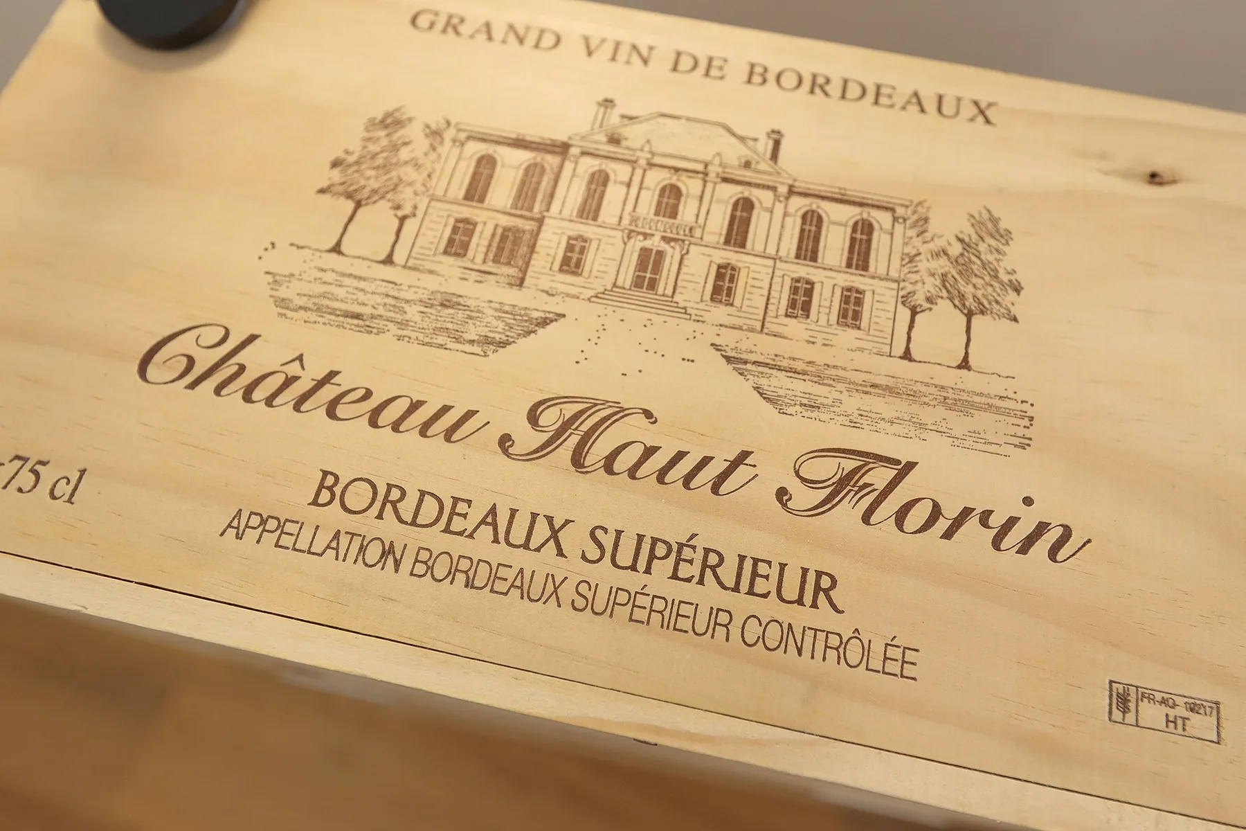 A close-up of a wooden wine box with a printed vineyard illustration and label.