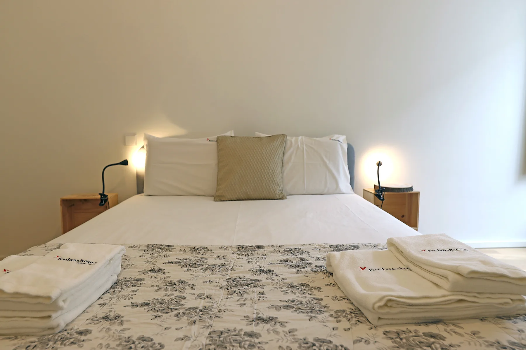 A bedroom with a neatly made bed and folded towels.