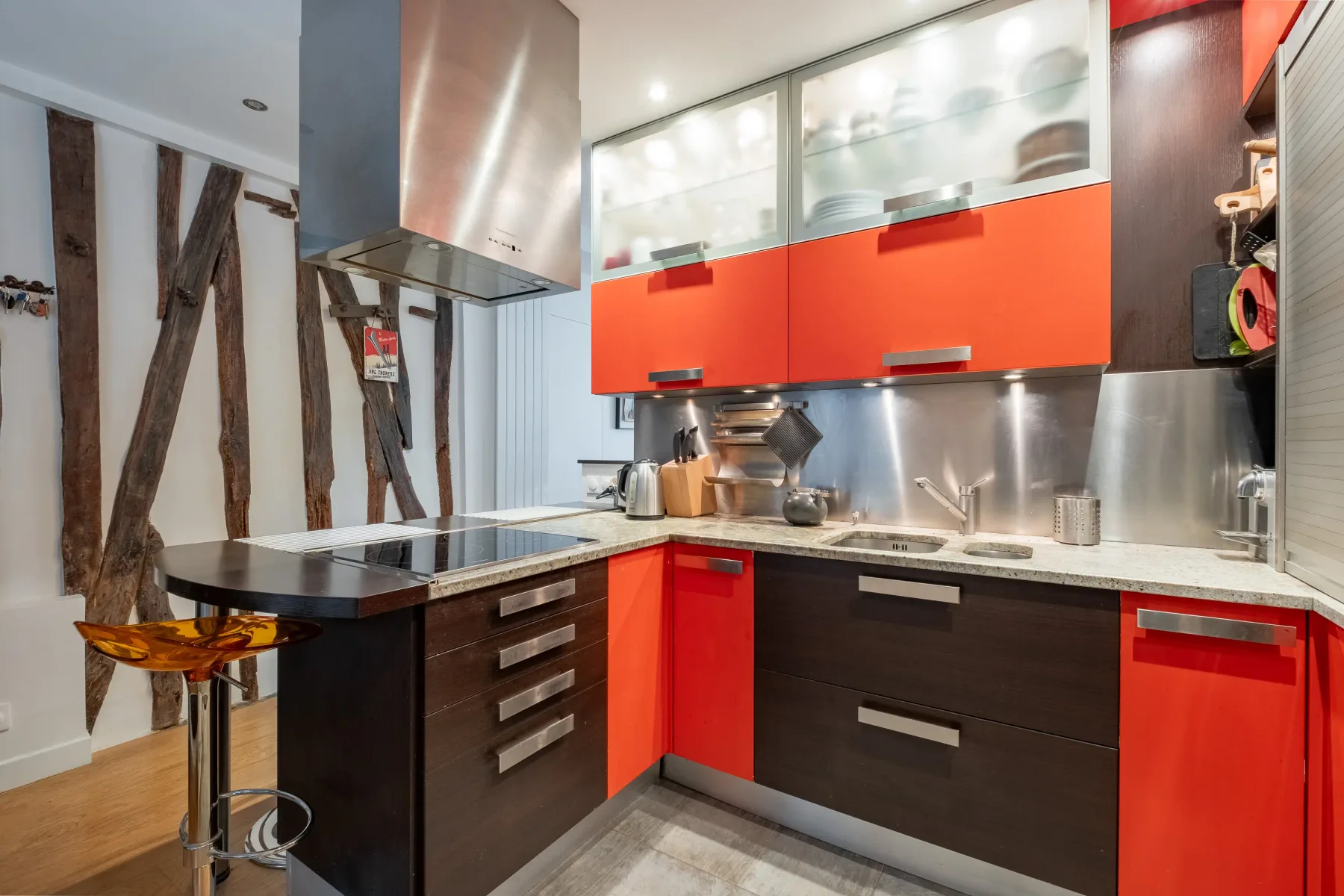 A modern kitchen with red cabinets, dark drawers, and a central island.