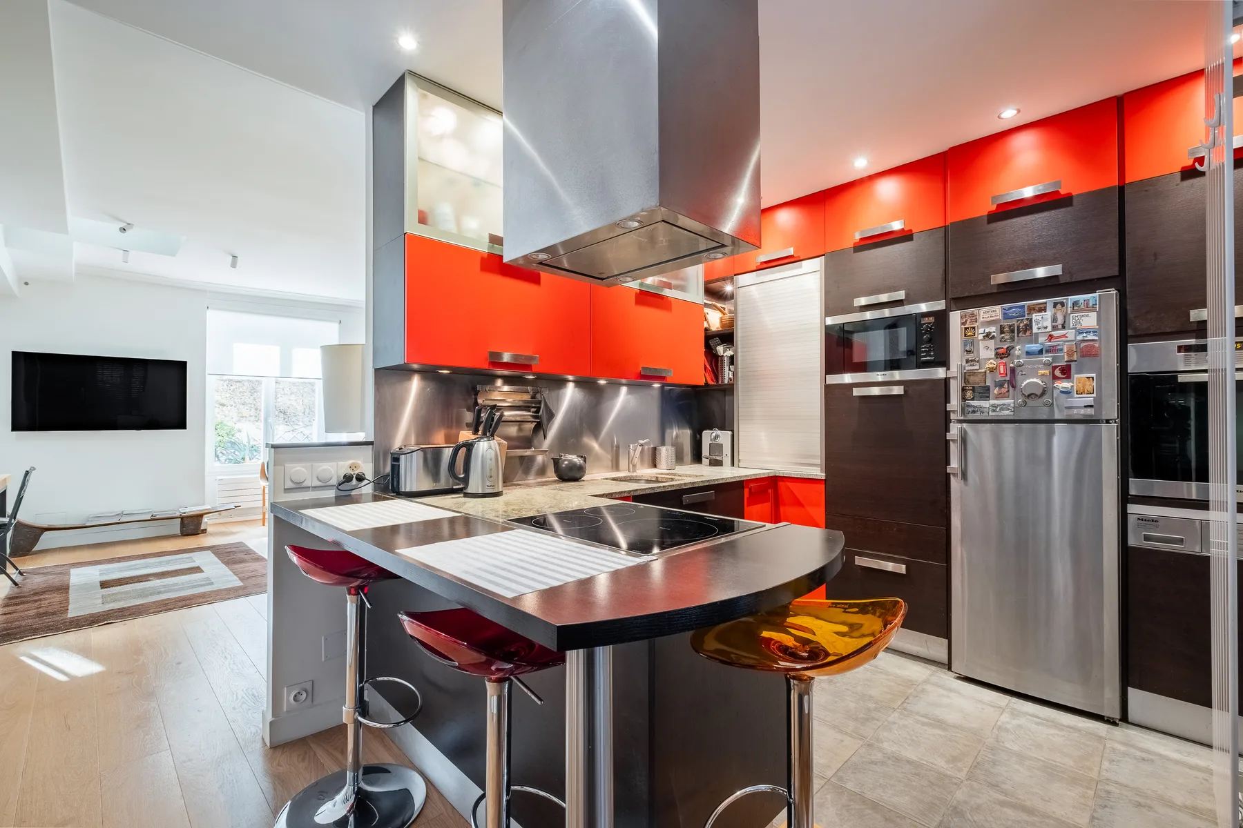 A modern kitchen with a central island and a living area visible beyond.