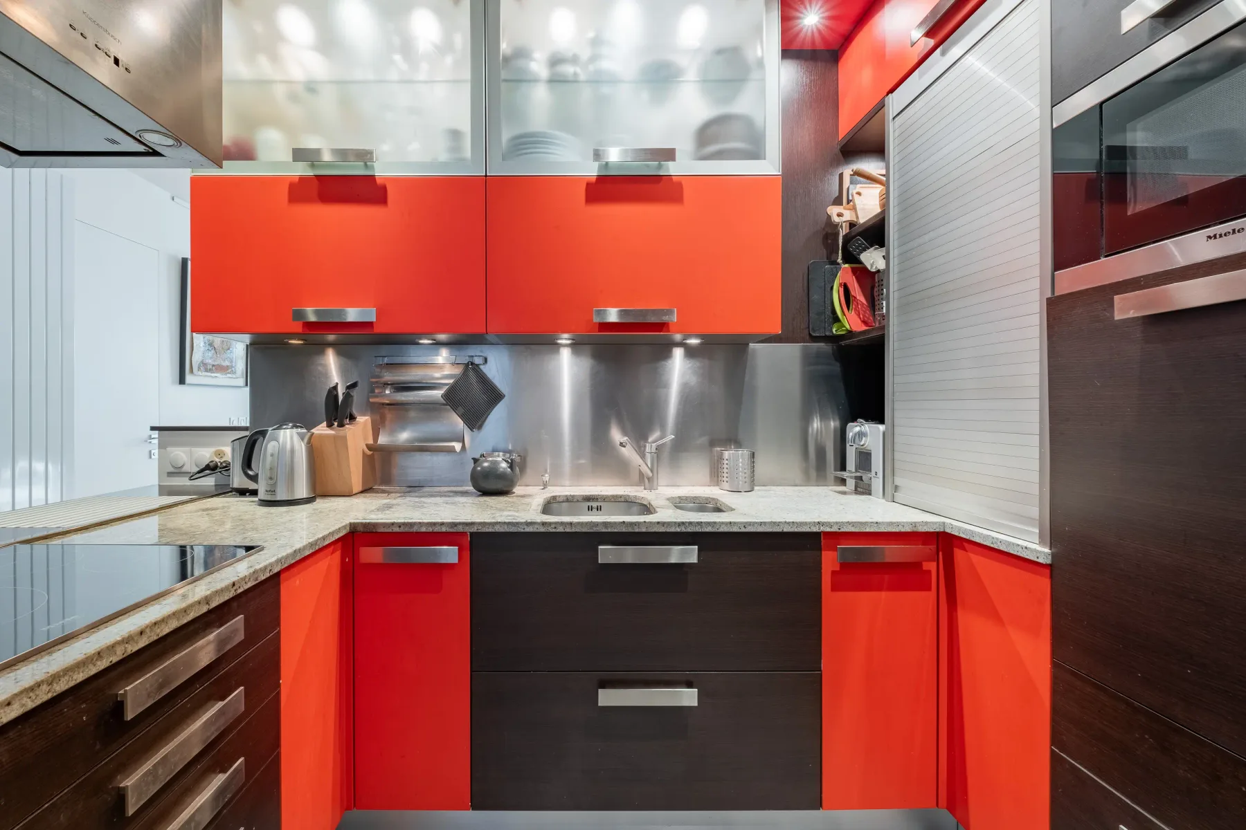 A modern kitchen with red cabinets and stainless steel appliances.