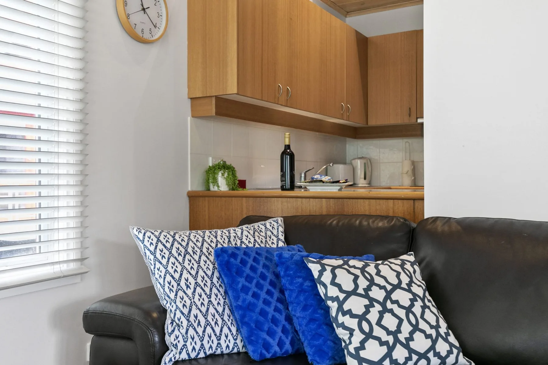 A living area with dark seating and a compact kitchen behind it.