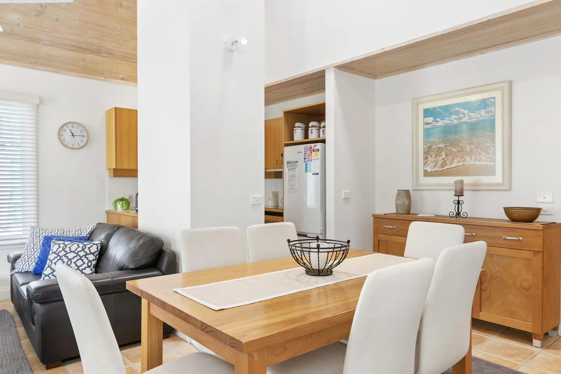 A dining area with a wooden table and seating beside a living area.