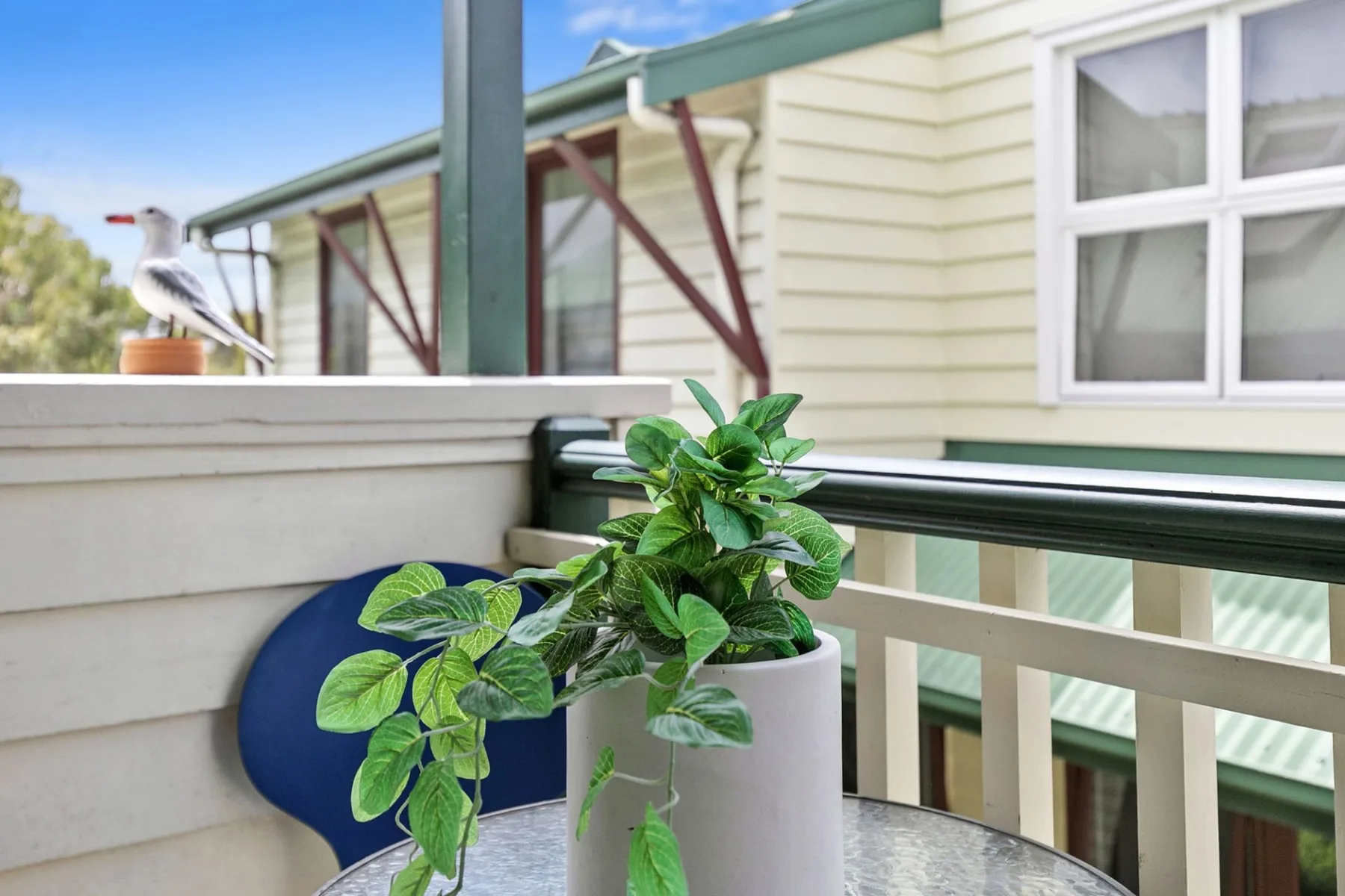 A small balcony with a potted plant beside a cream-colored exterior wall.