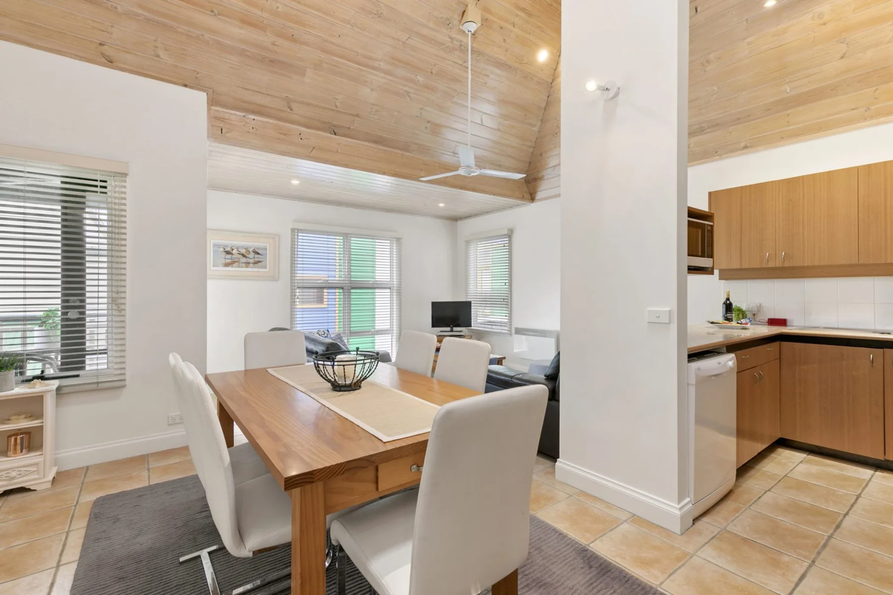 A dining area with a wooden table and an open kitchen.