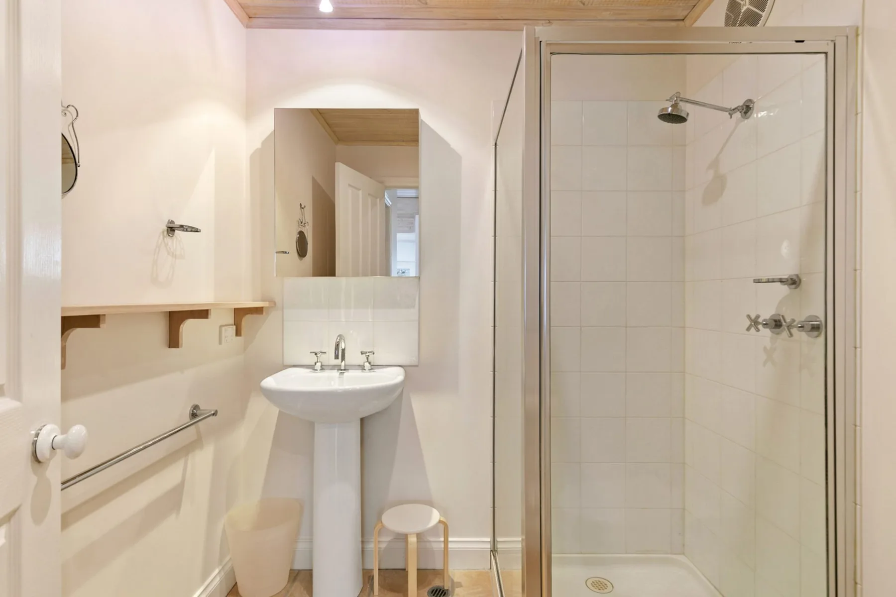 A bright bathroom with a pedestal sink and glass-enclosed shower.