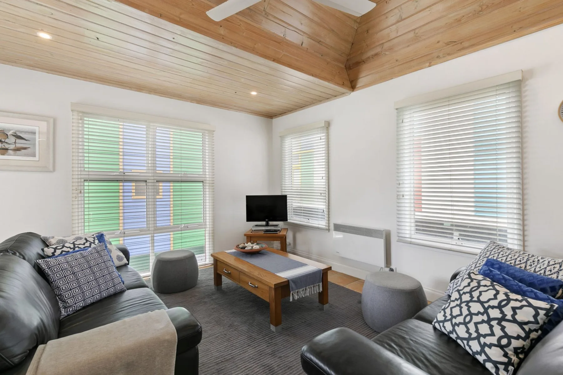 A living room with seating, a coffee table, and large windows.