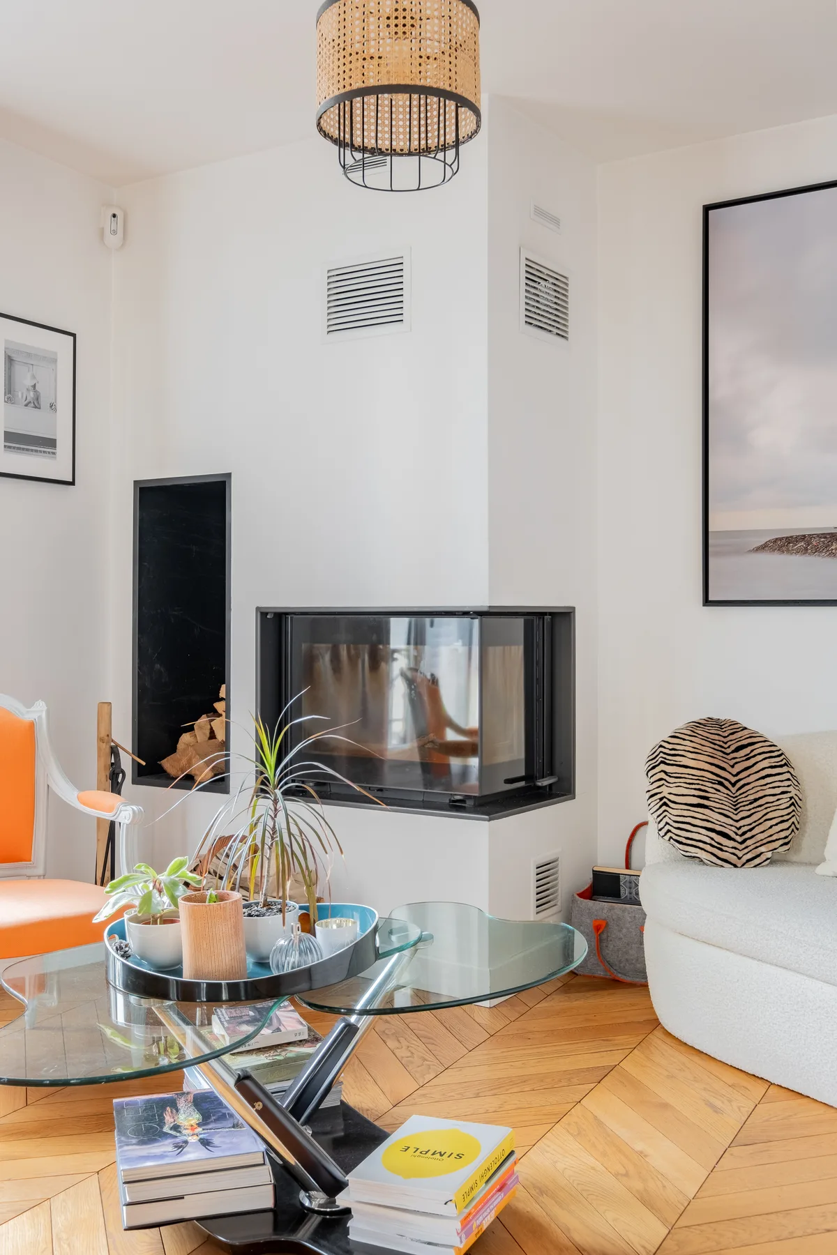 A bright living room with a glass coffee table and a fireplace.