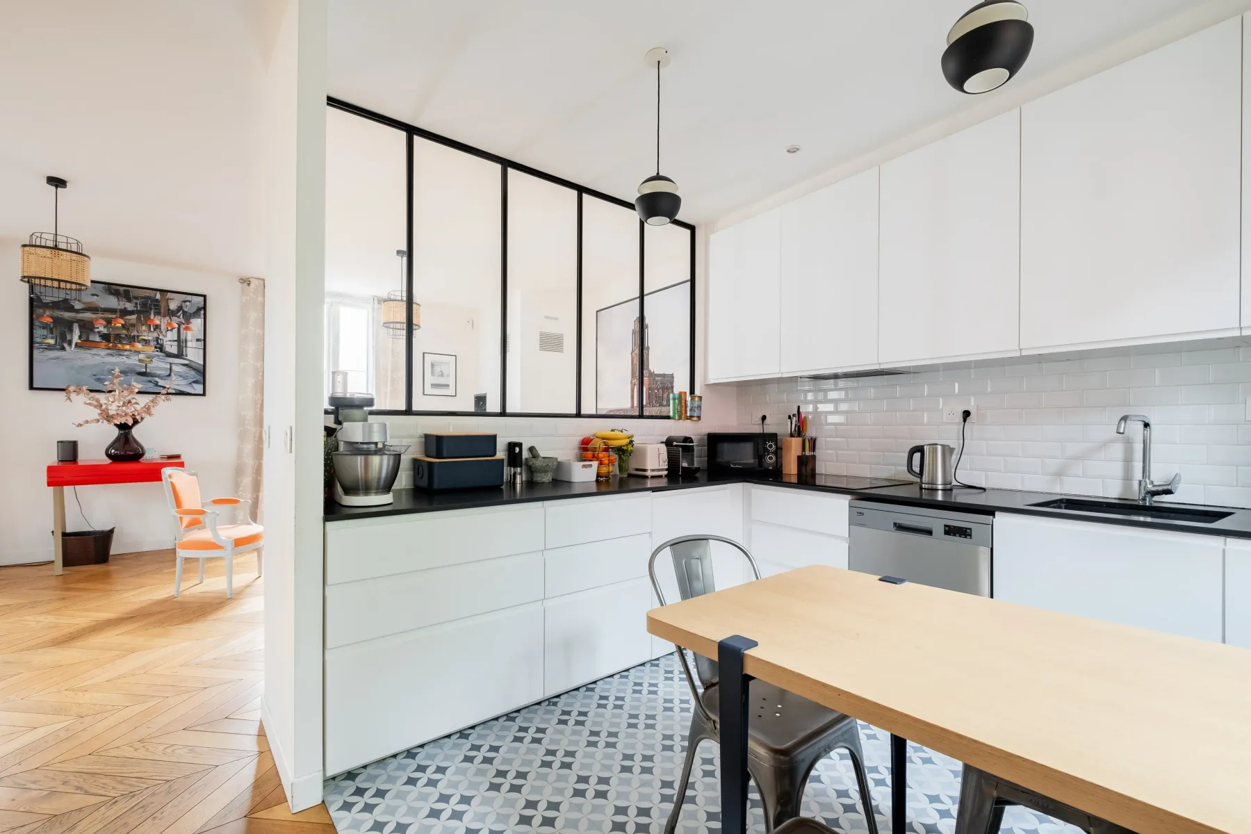 A bright kitchen with white cabinets, a tiled backsplash, and a dining table.