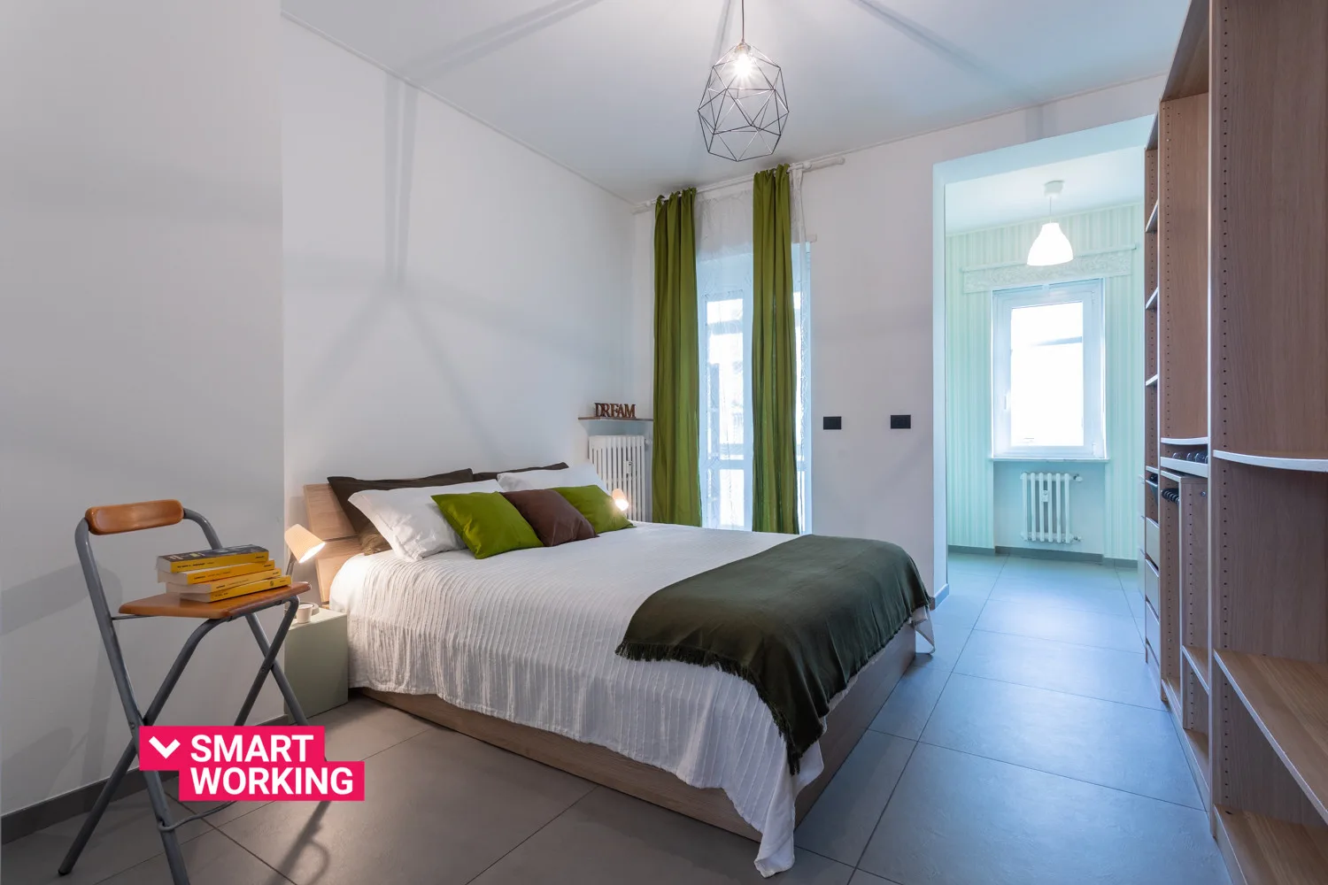 A bedroom with a neatly made bed and green curtains beside an open doorway.