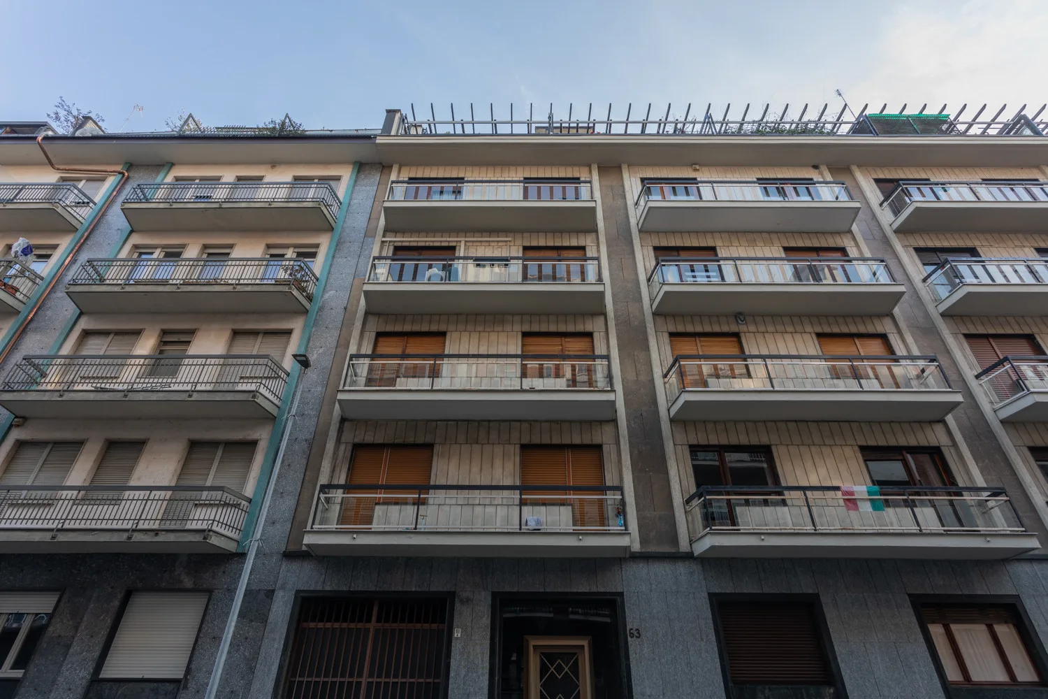 A multi-story apartment building with rows of balconies beneath a clear sky.