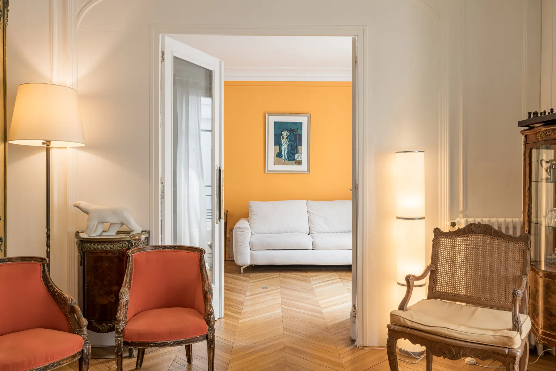 Una sala de estar con asientos tapizados y un cuadro en la pared naranja.
