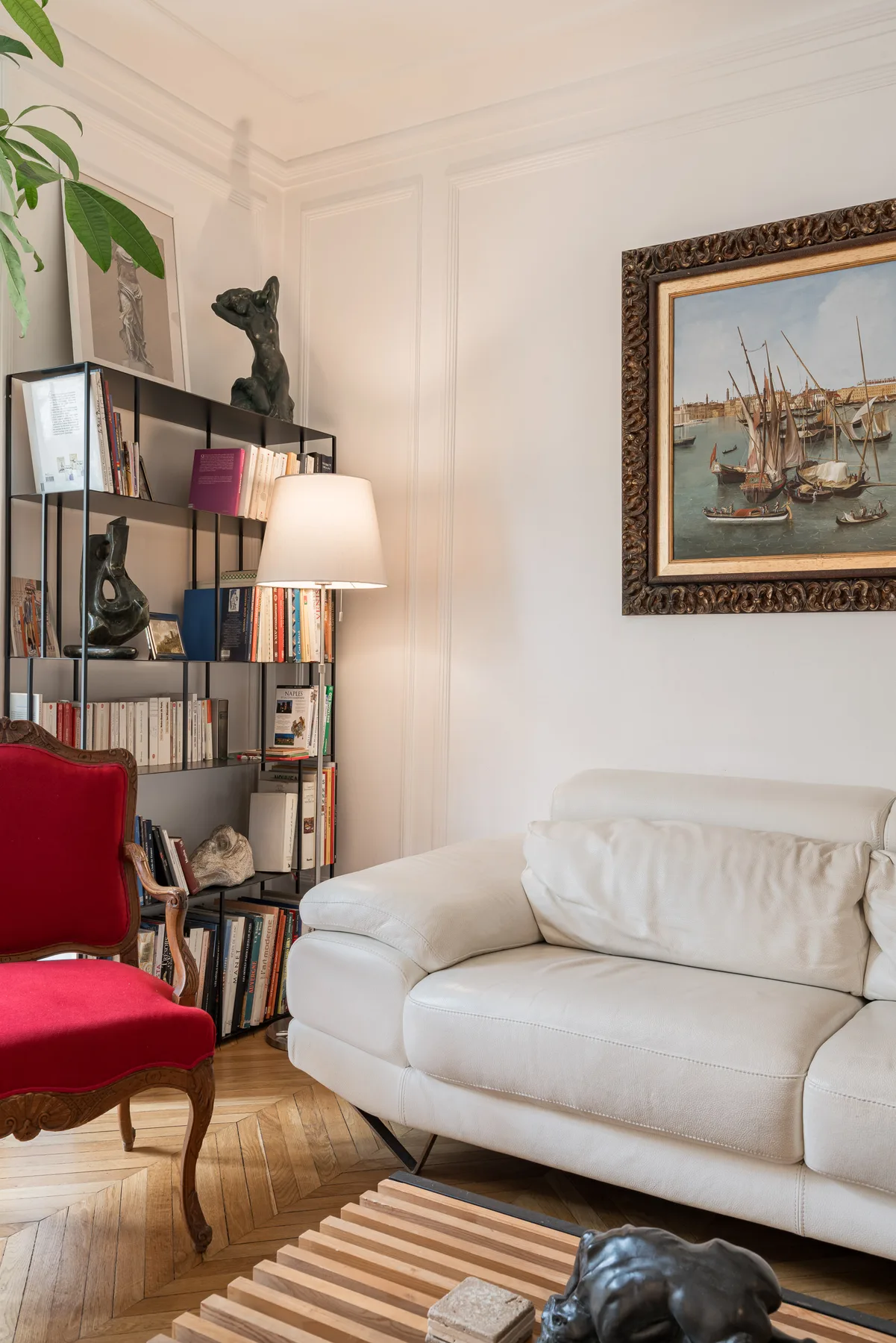 Una sala de estar con un sofá blanco, estanterías y un cuadro enmarcado.