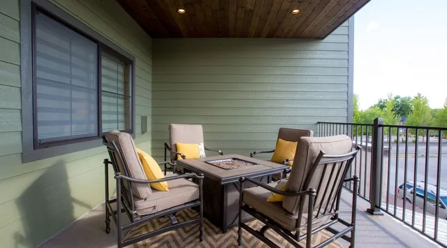 A covered patio with outdoor seating and a railing.