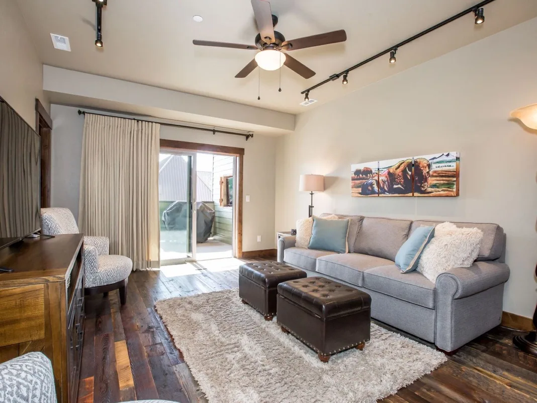 A living room with a gray sectional, a rug, and sliding glass doors.