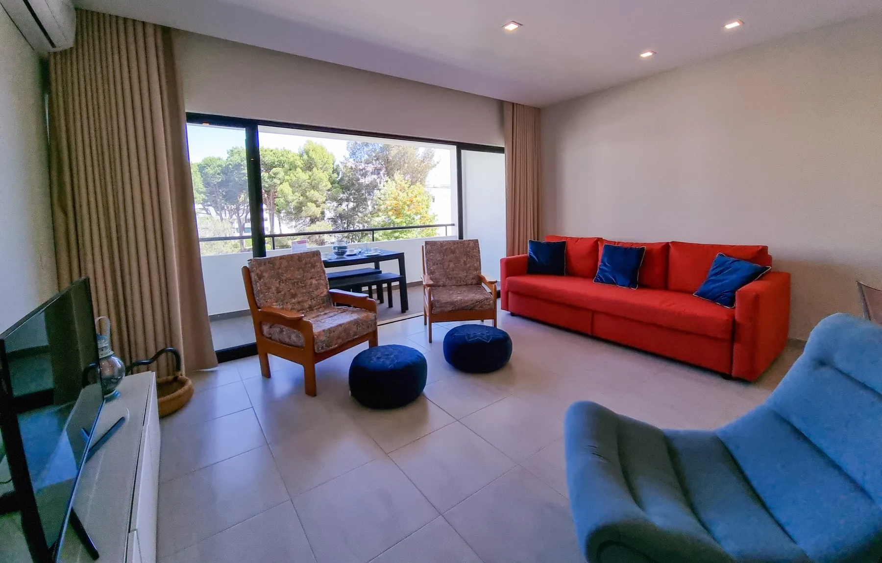 Una sala de estar con asientos rojos y una gran ventana con vistas a los árboles.