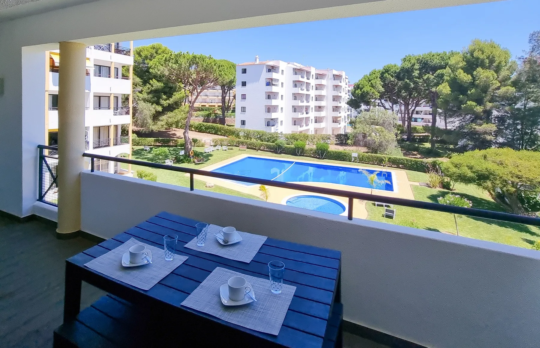 Una zona de comedor en el balcón da a una piscina y jardines.