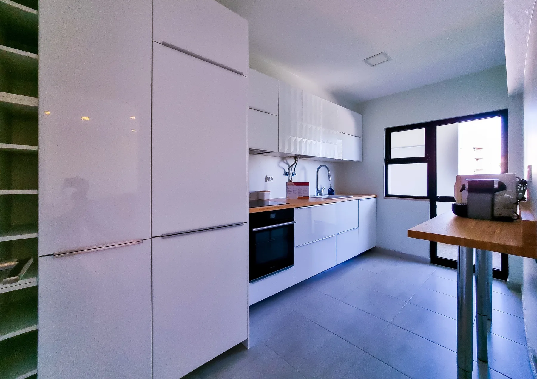 Una cocina luminosa y moderna con armarios blancos y una encimera de madera.