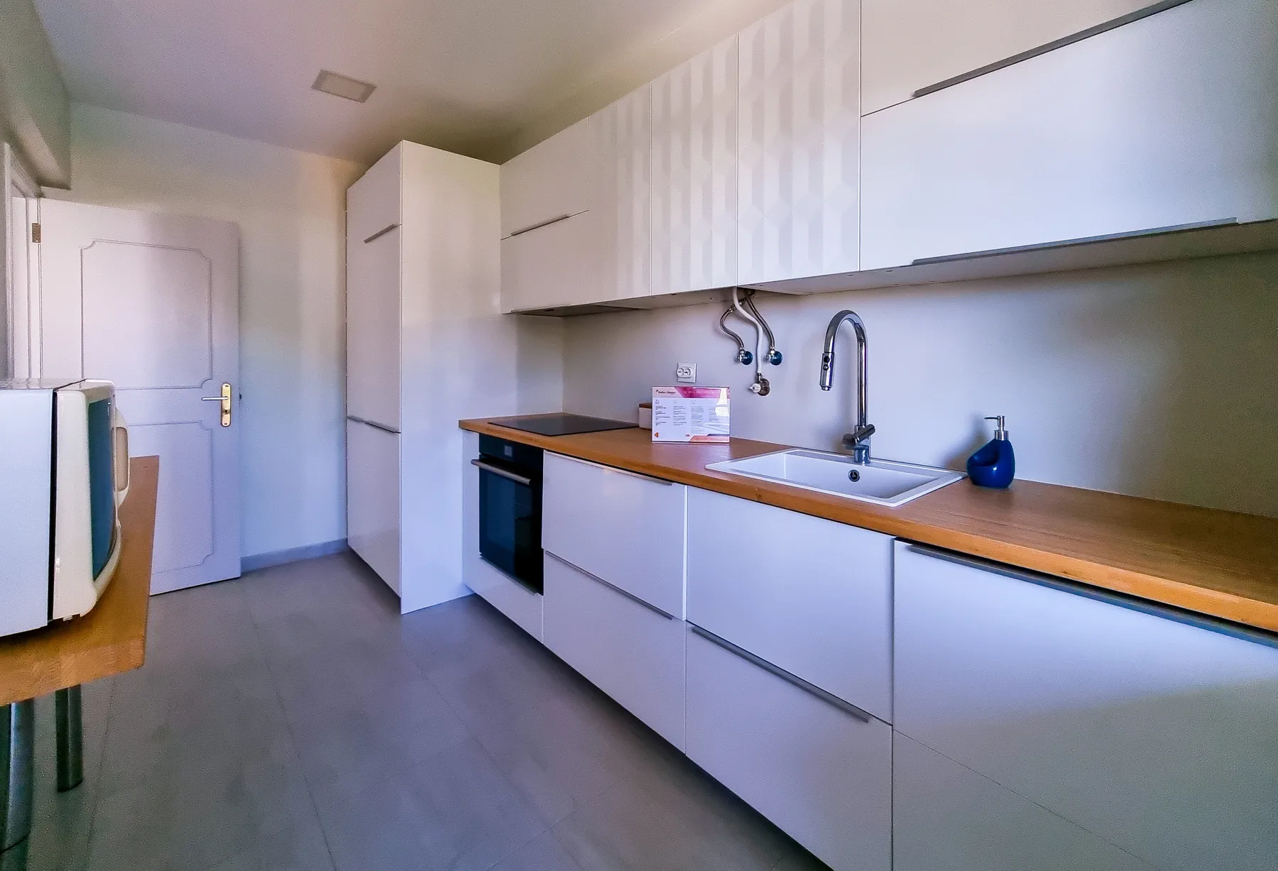 Una cocina moderna con armarios blancos, una encimera y un fregadero.