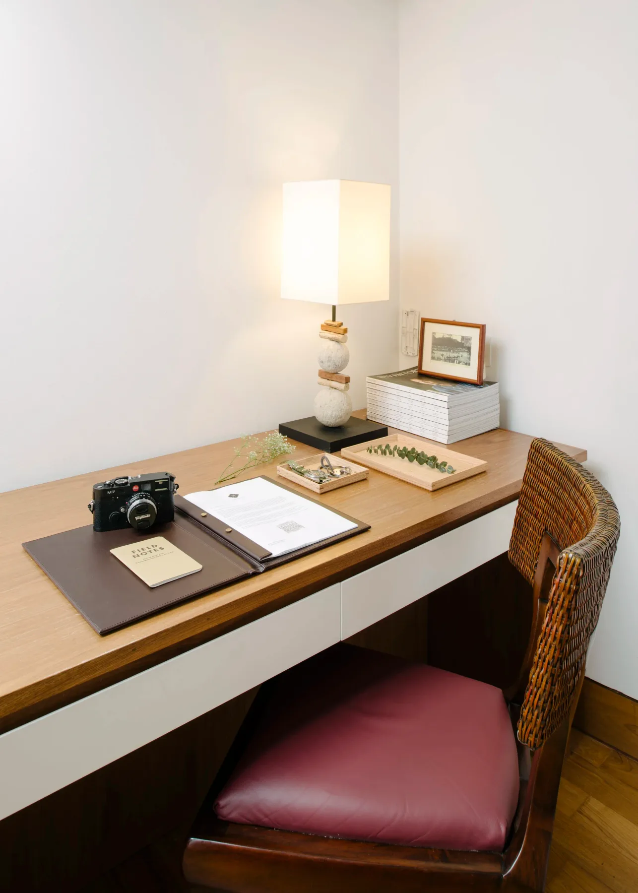 Escritorio de madera con una lámpara, cuadernos y objetos decorativos.