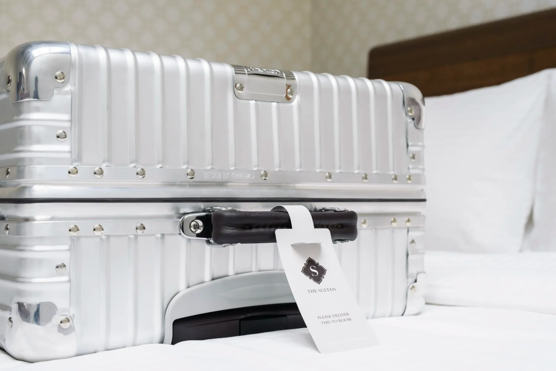 Maleta sobre una cama con ropa de cama blanca.