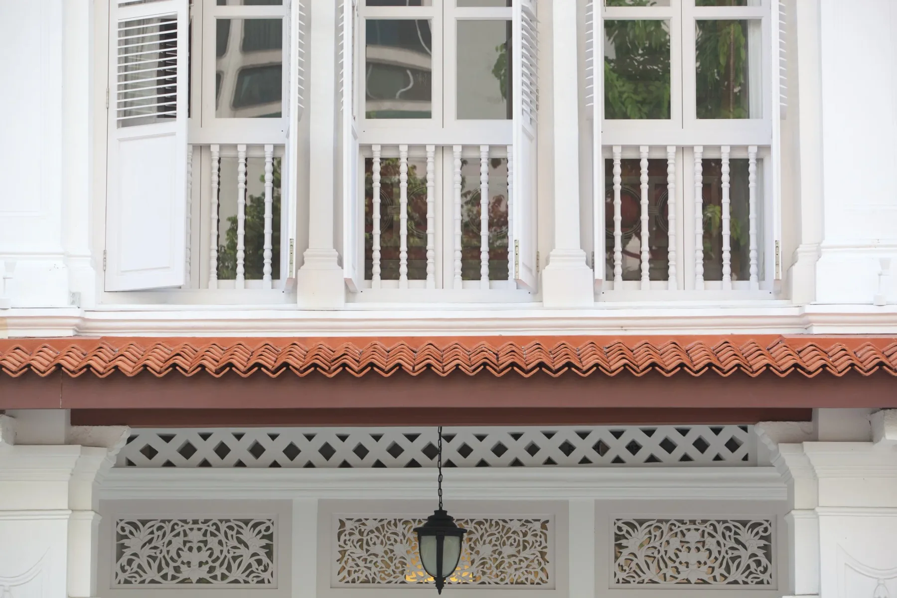 Fachada blanca de un edificio histórico con balcón, balaustres decorativos y tejado de tejas de terracota.
