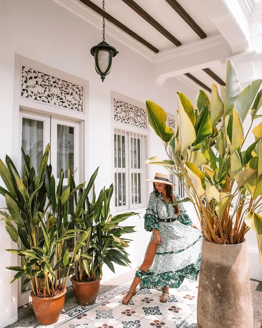 Exterior de un edificio blanco con elementos decorativos de madera y suelo de baldosas con motivos.