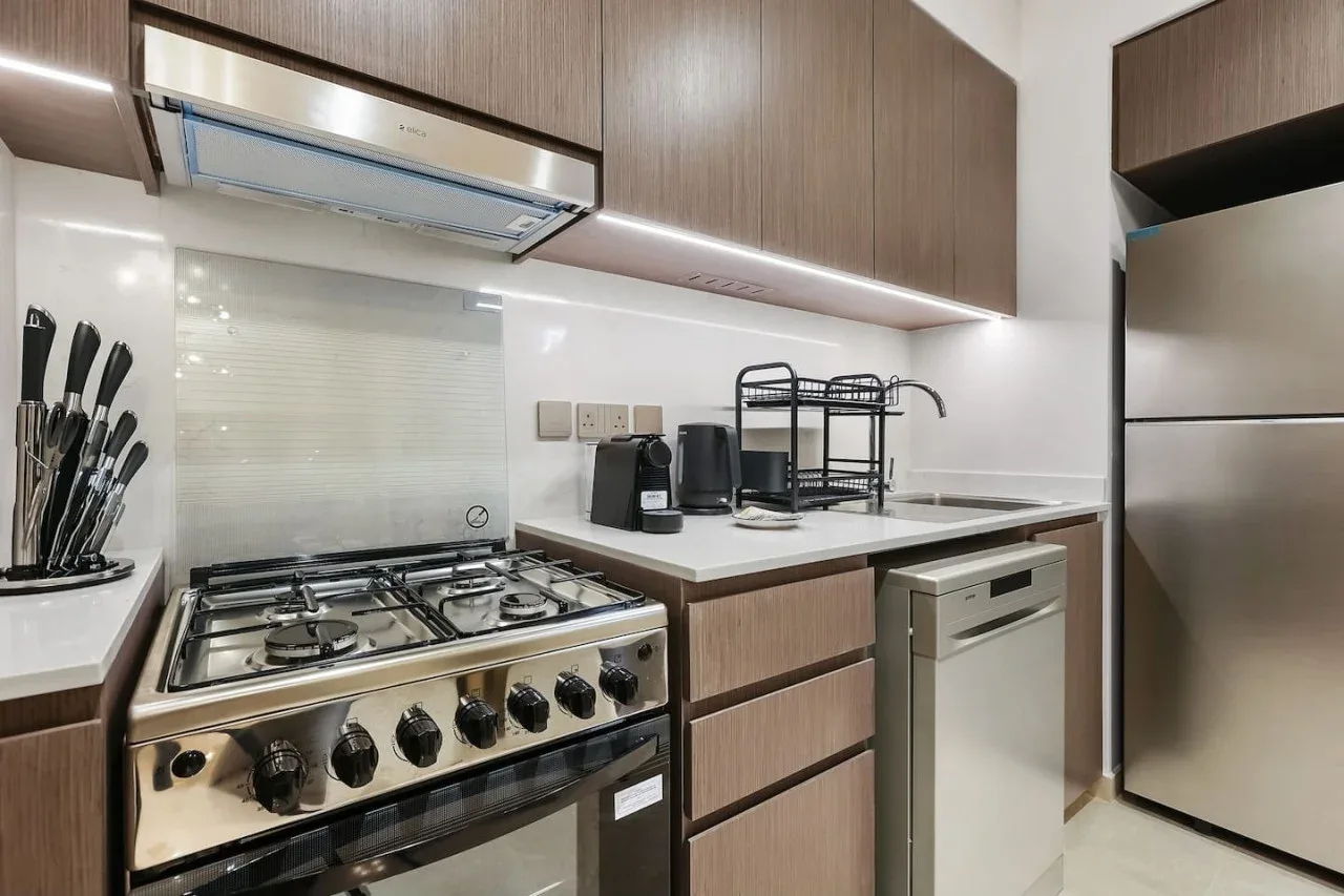 Una cocina moderna con estufa de gas, pequeños electrodomésticos y gabinetes de madera.