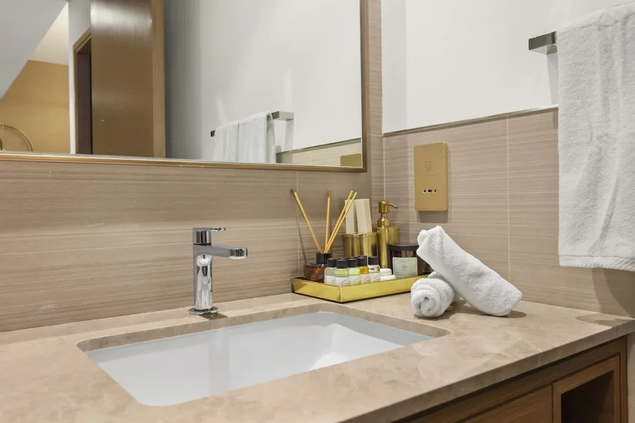 Un lavabo de baño con espejo y toallas dobladas.