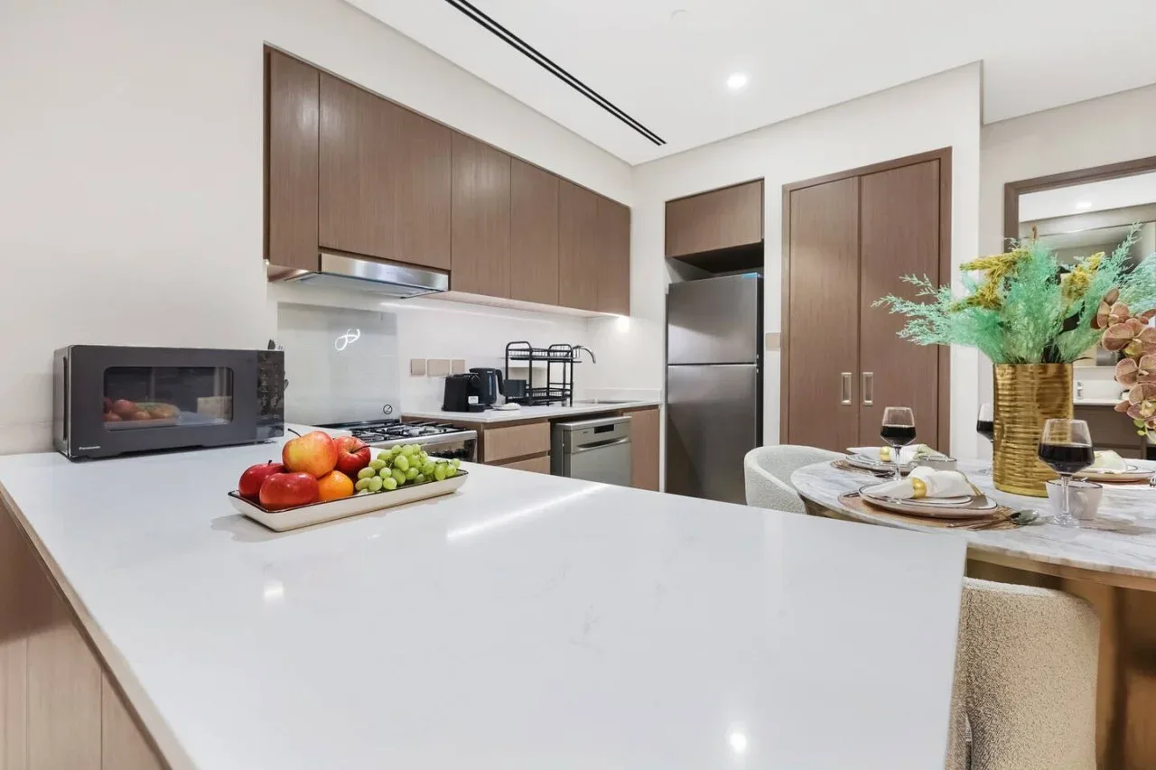 Una cocina moderna con una gran isla blanca y gabinetes oscuros.