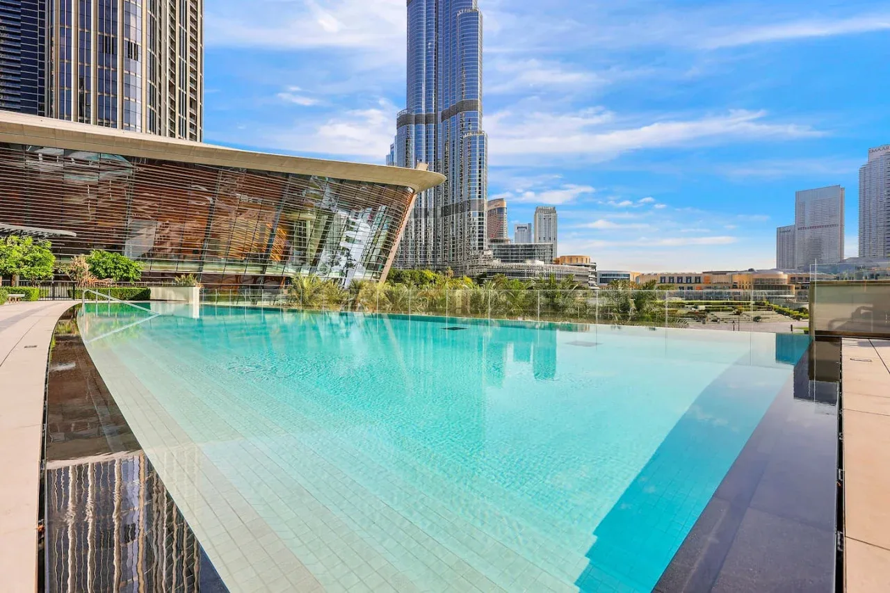 Una piscina al aire libre está rodeada de modernos edificios altos.