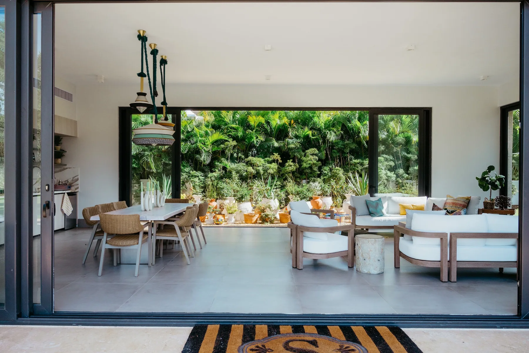 Una luminosa sala de estar y comedor se abre a grandes ventanales con vistas a la vegetación.