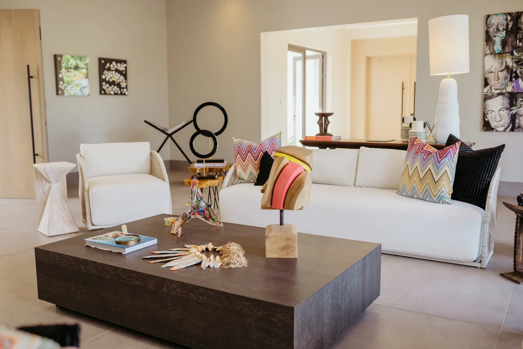 Una sala luminosa con un sofá blanco y una mesa de centro oscura.