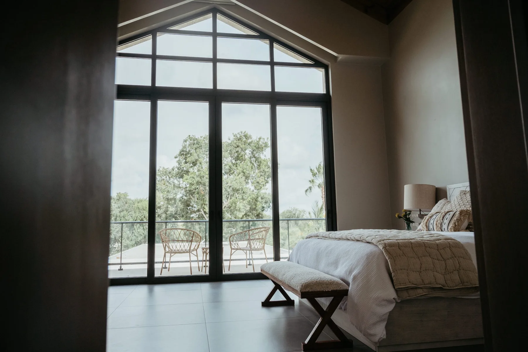 Un dormitorio con un gran ventanal y vistas a los árboles.