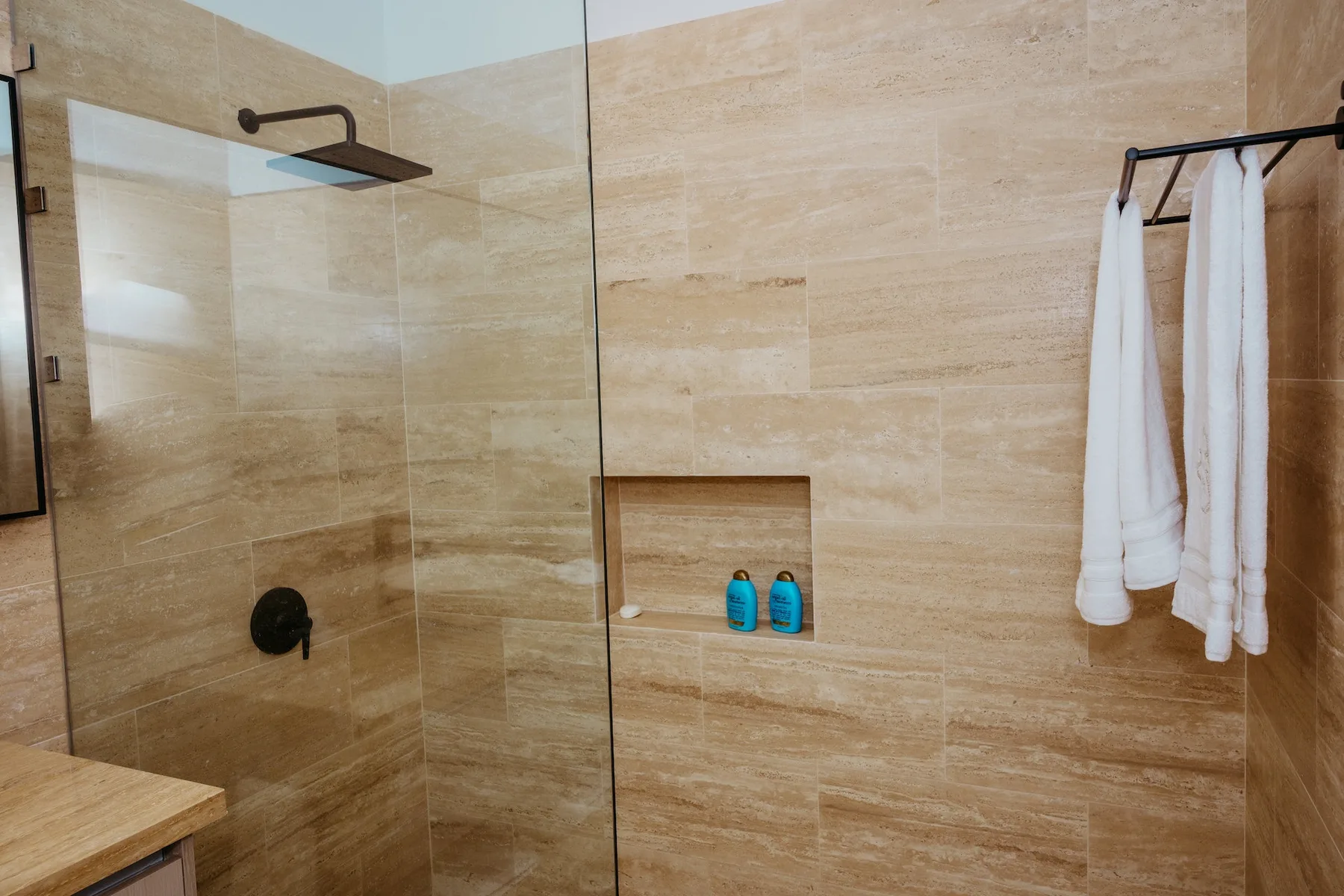 Una ducha de baño con azulejos, un nicho empotrado y toallas colgadas.