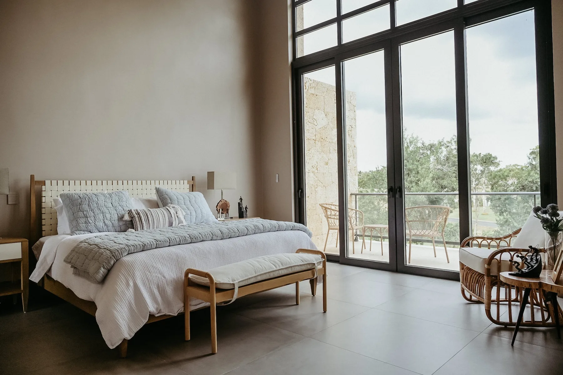 Un dormitorio con una cama junto a grandes ventanales que dan a un balcón.