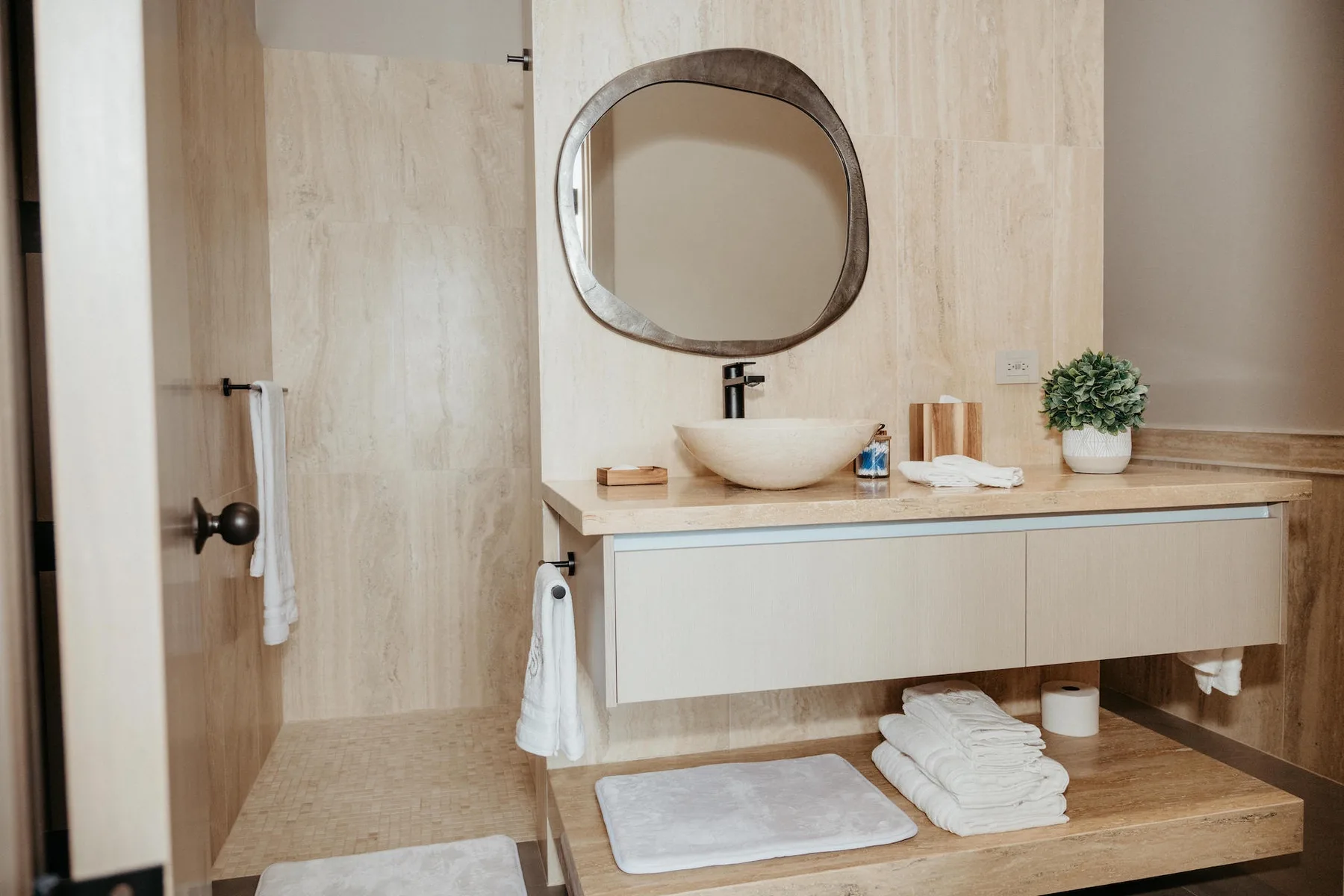 Un tocador de baño con lavabo sobre encimera, espejo y toallas dobladas.