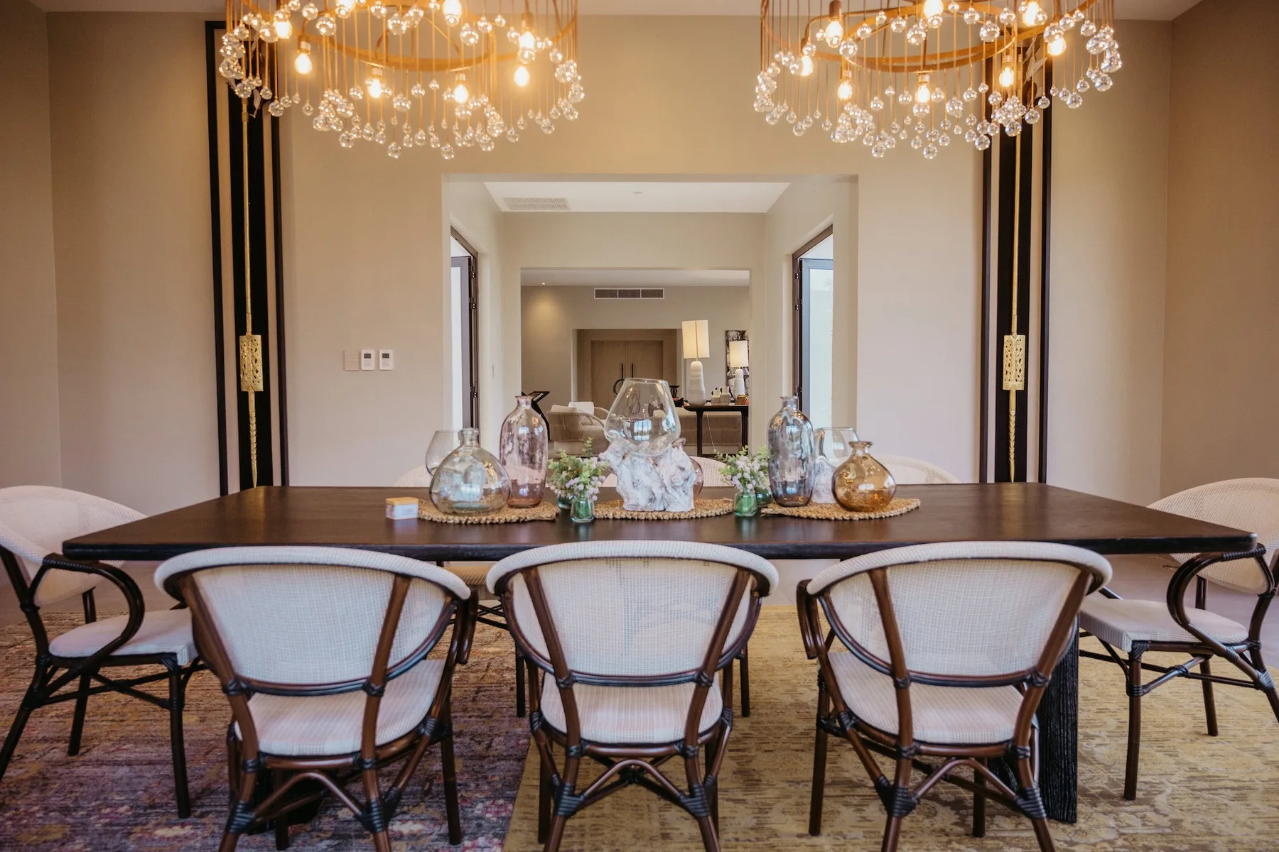 Un comedor formal presenta una mesa larga, asientos tapizados y lámparas decorativas.
