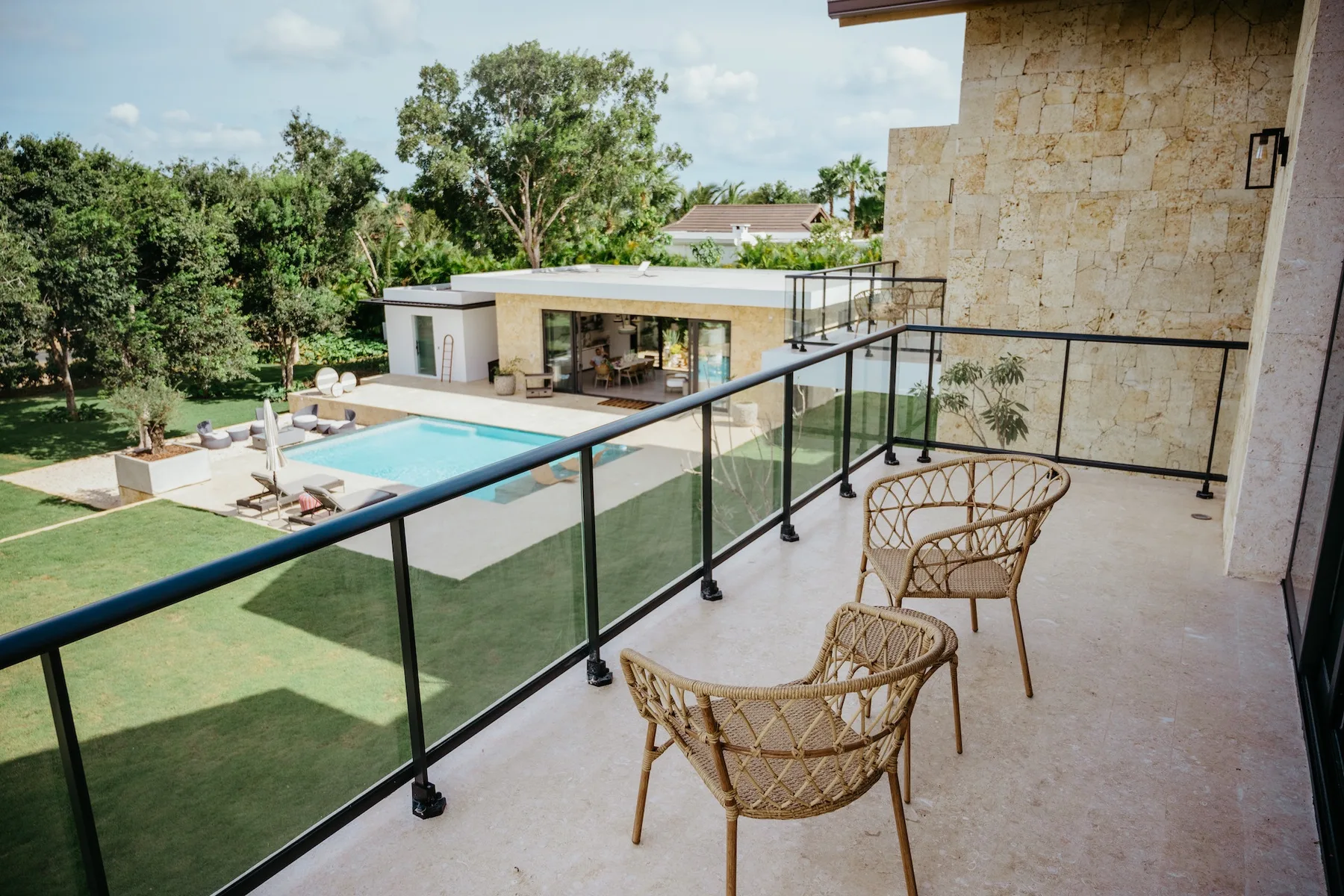 Un balcón da a una piscina, un césped y un jardín ajardinado.