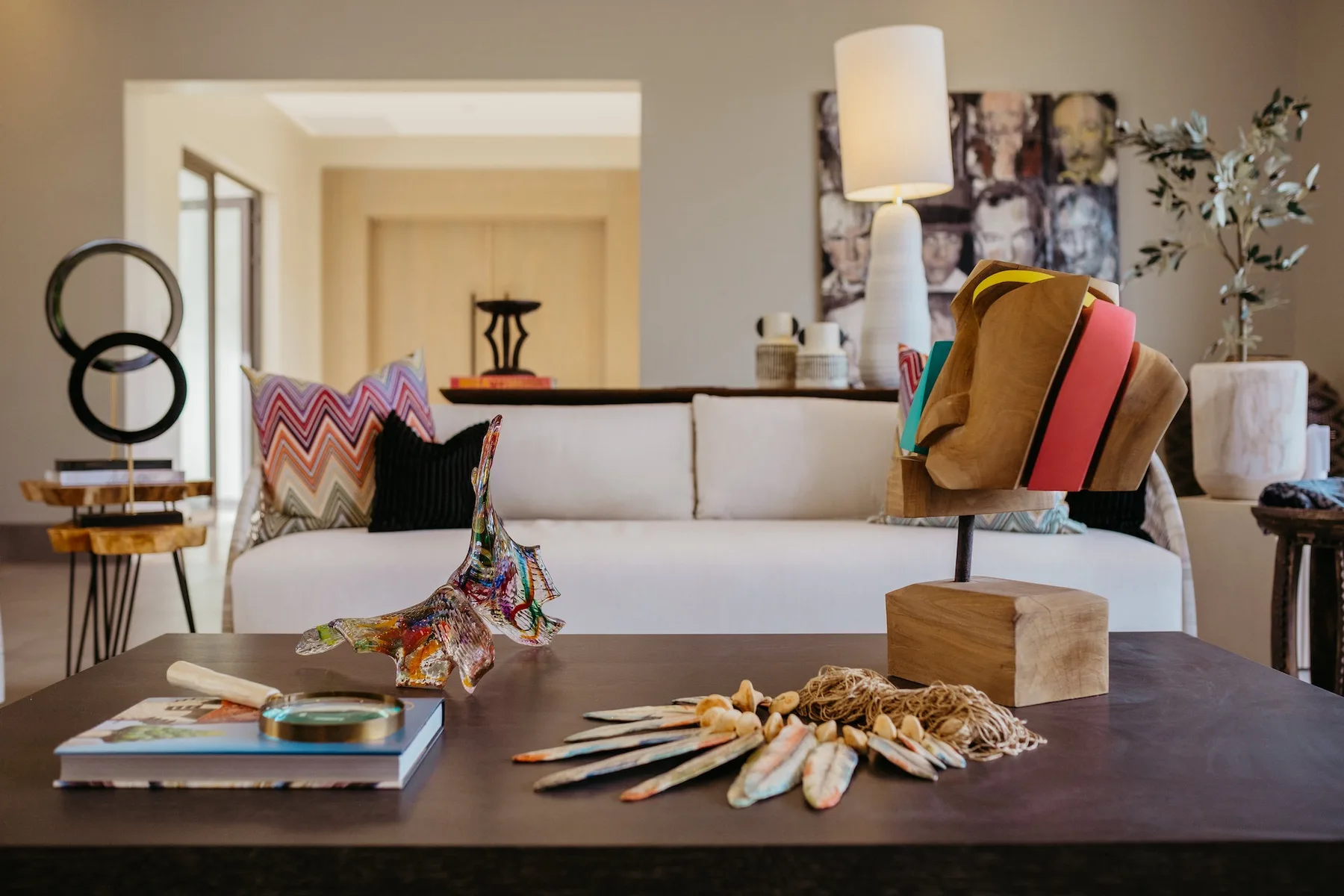 Una sala de estar con un sofá blanco y una mesa de centro oscura con objetos decorativos.