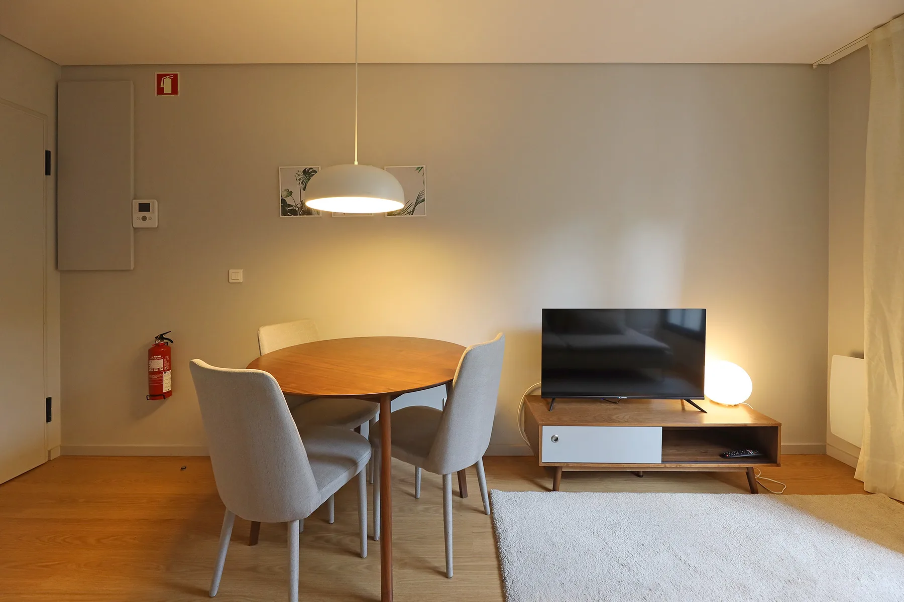 Una sala de estar con mesa de comedor, asientos y un televisor.