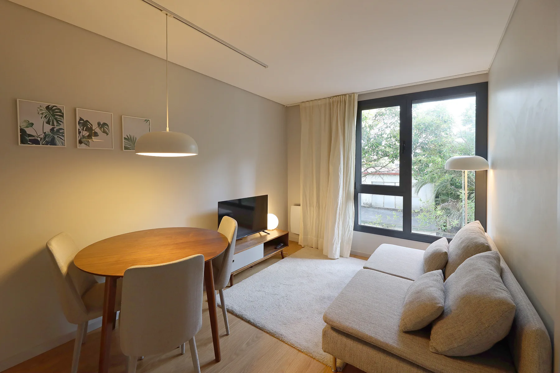 Sala de estar con mesa de comedor, asientos y grandes ventanales.
