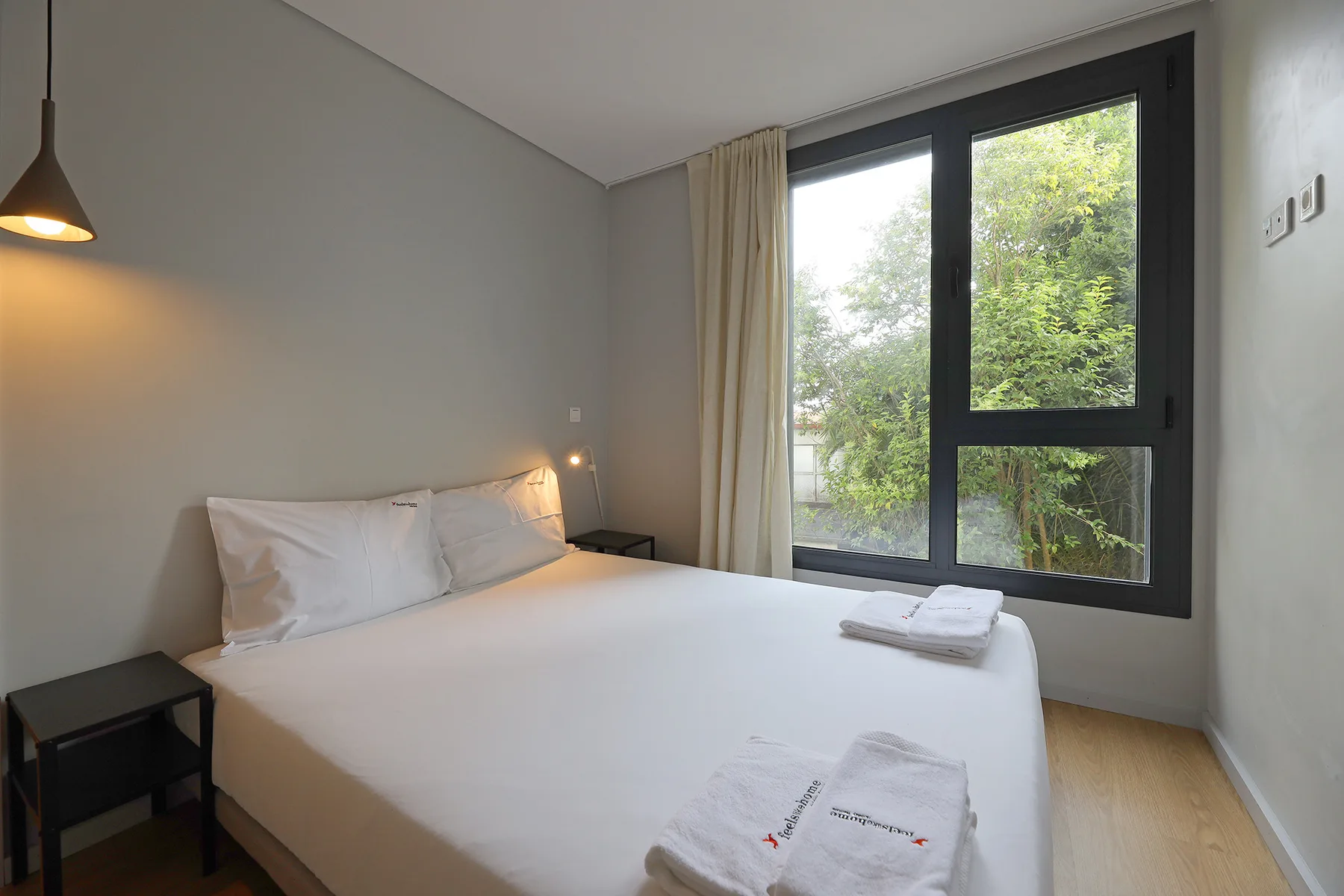 Un dormitorio con una cama bien hecha junto a una ventana grande.